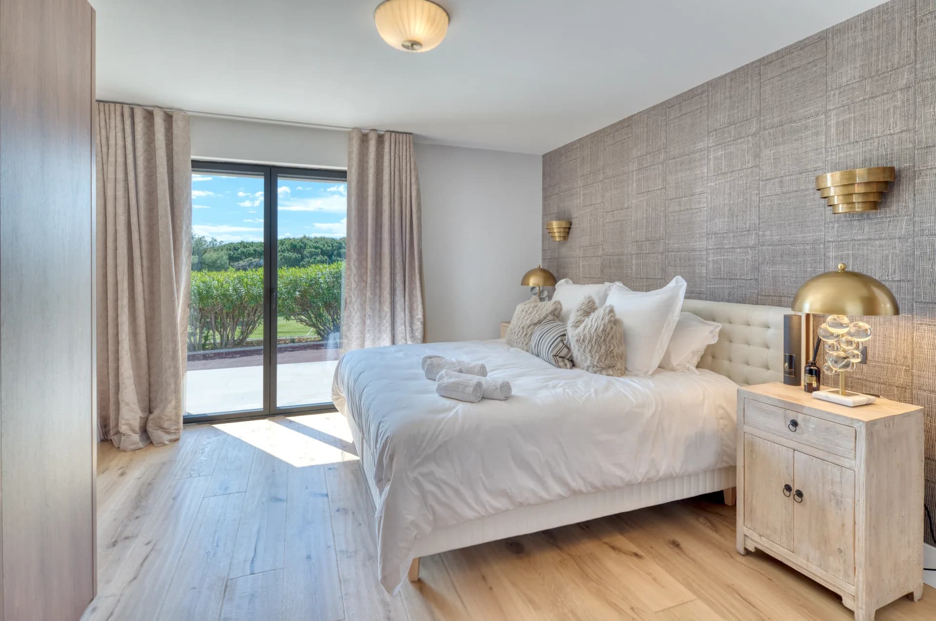 Chambre, tête de lit capitonnée, mur tissé et baie sur la terrasse