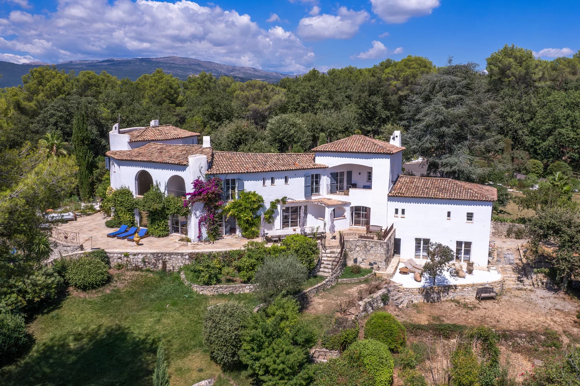 La bastide vue du ciel, terrasse de pierre et collines derrière