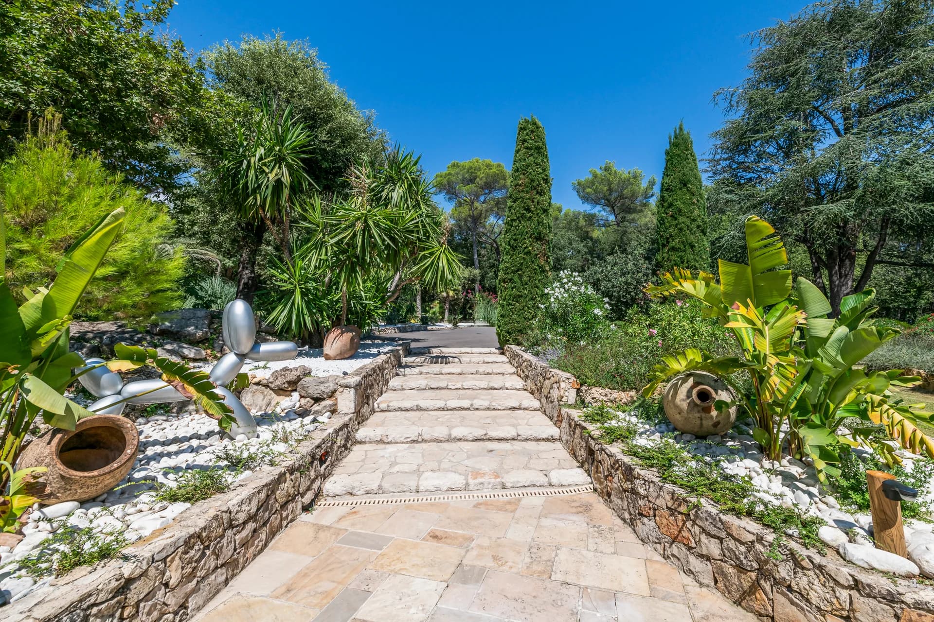 Allée pavée du jardin, cyprès, bananiers et jarres en terre cuite
