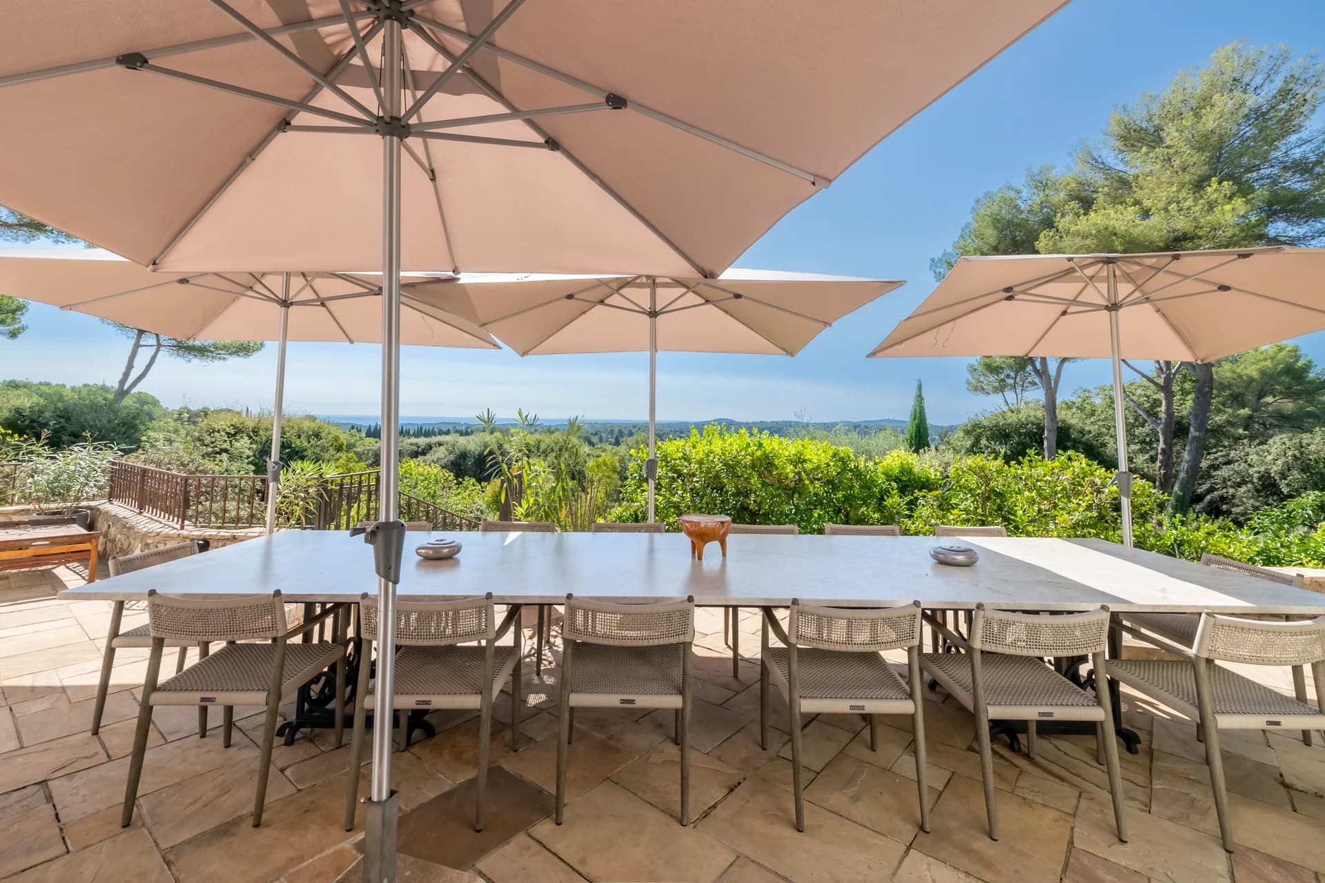 Table de terrasse sous les parasols, vue sur les collines et la mer