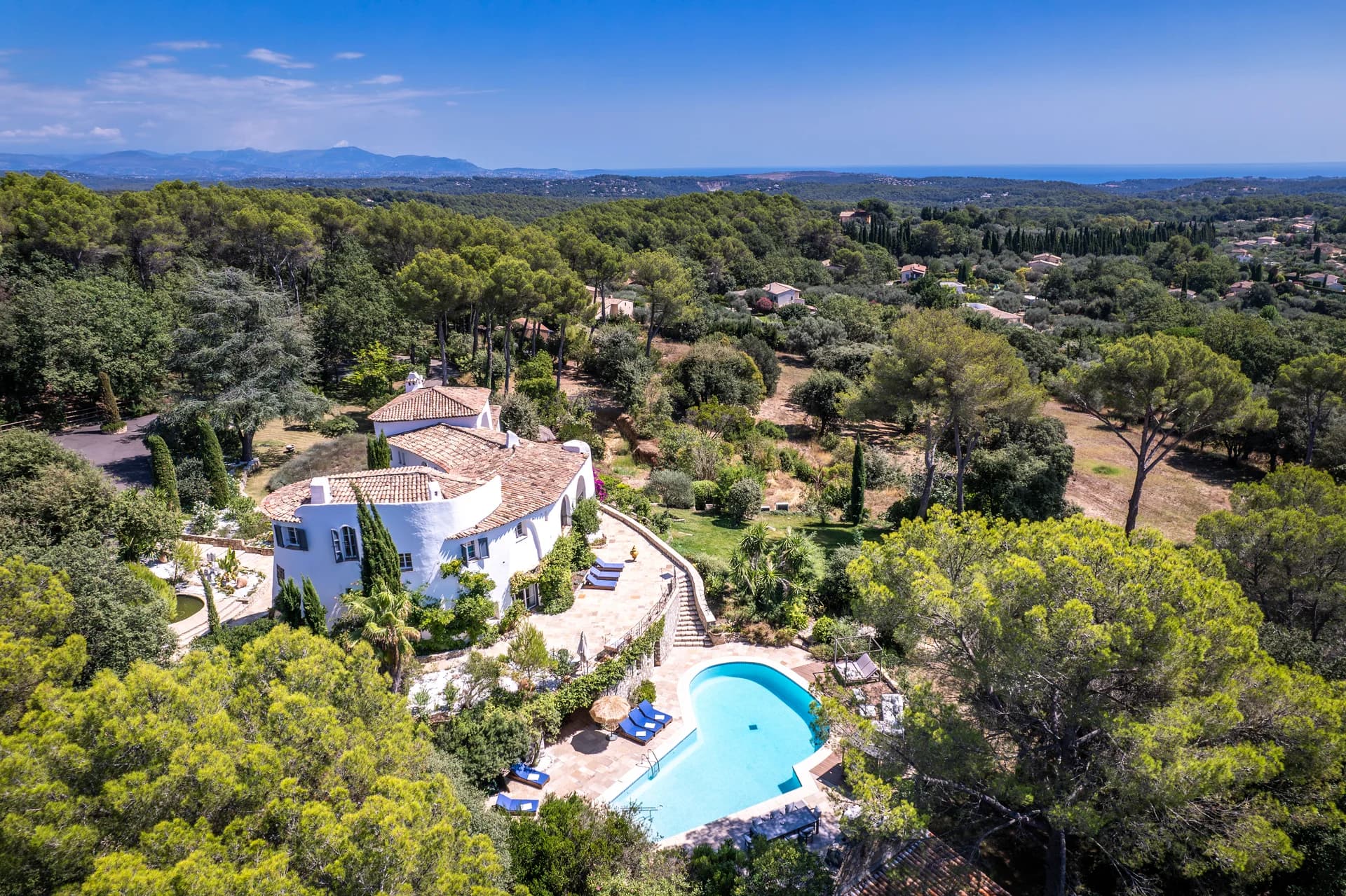 Vue aérienne : la bastide, la piscine en contrebas et la mer au loin