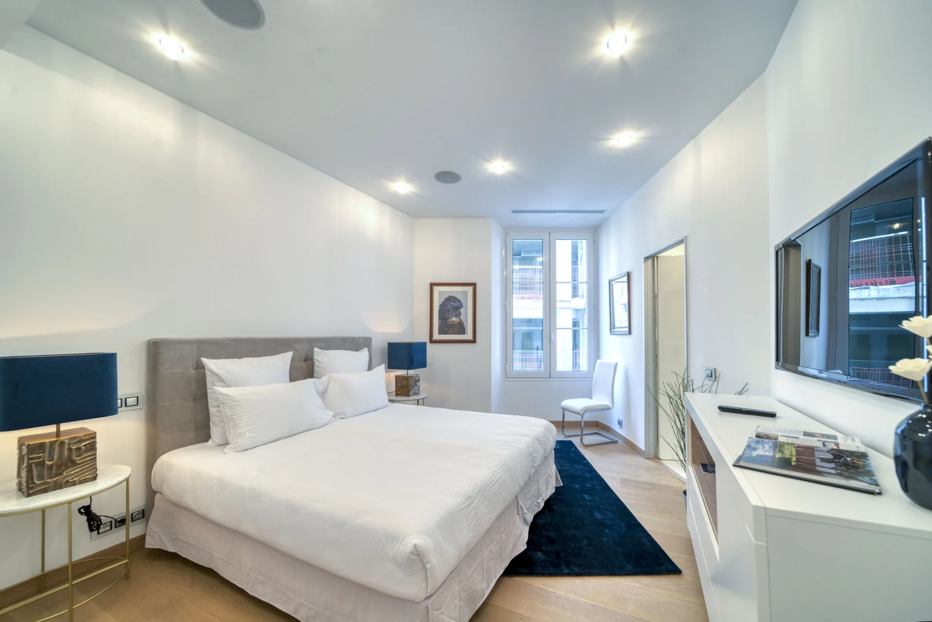 Chambre au tapis bleu, bureau et fenêtre sur cour