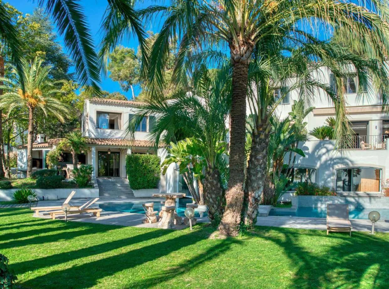Façade de la villa ouverte sur la pelouse et les palmiers