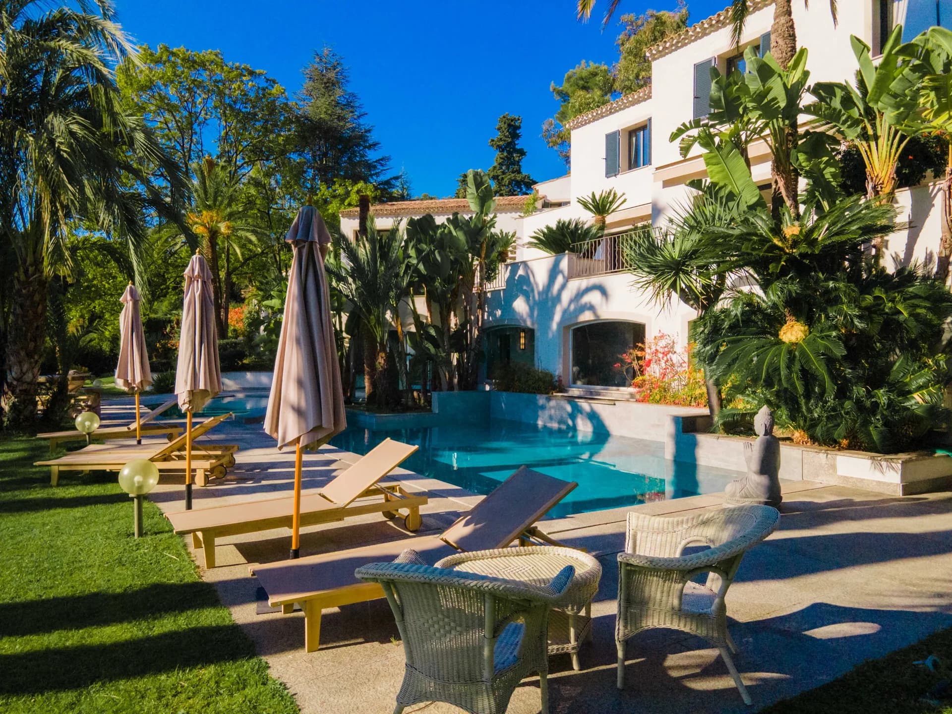Terrasse de la Villa Eternity : parasols, bains de soleil et piscine dans la palmeraie, à Saint-Paul-de-Vence