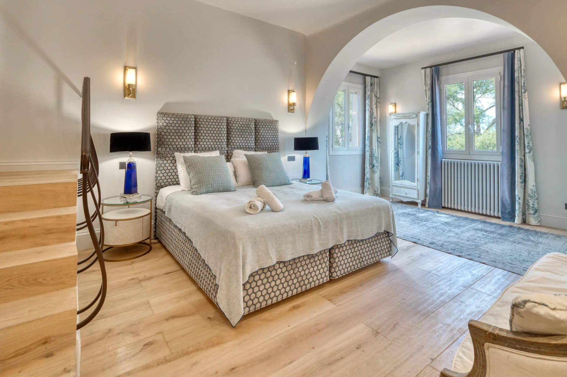Chambre, tête de lit capitonnée et arche ouvrant sur le coin salon