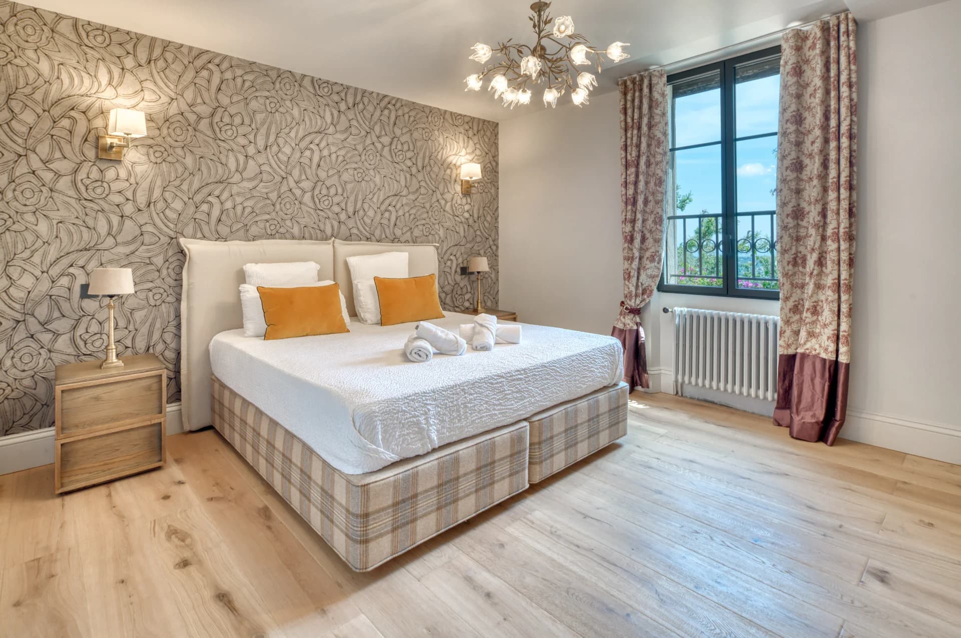 Chambre à tête de lit capitonnée, lustre fleuri et vue sur la vallée
