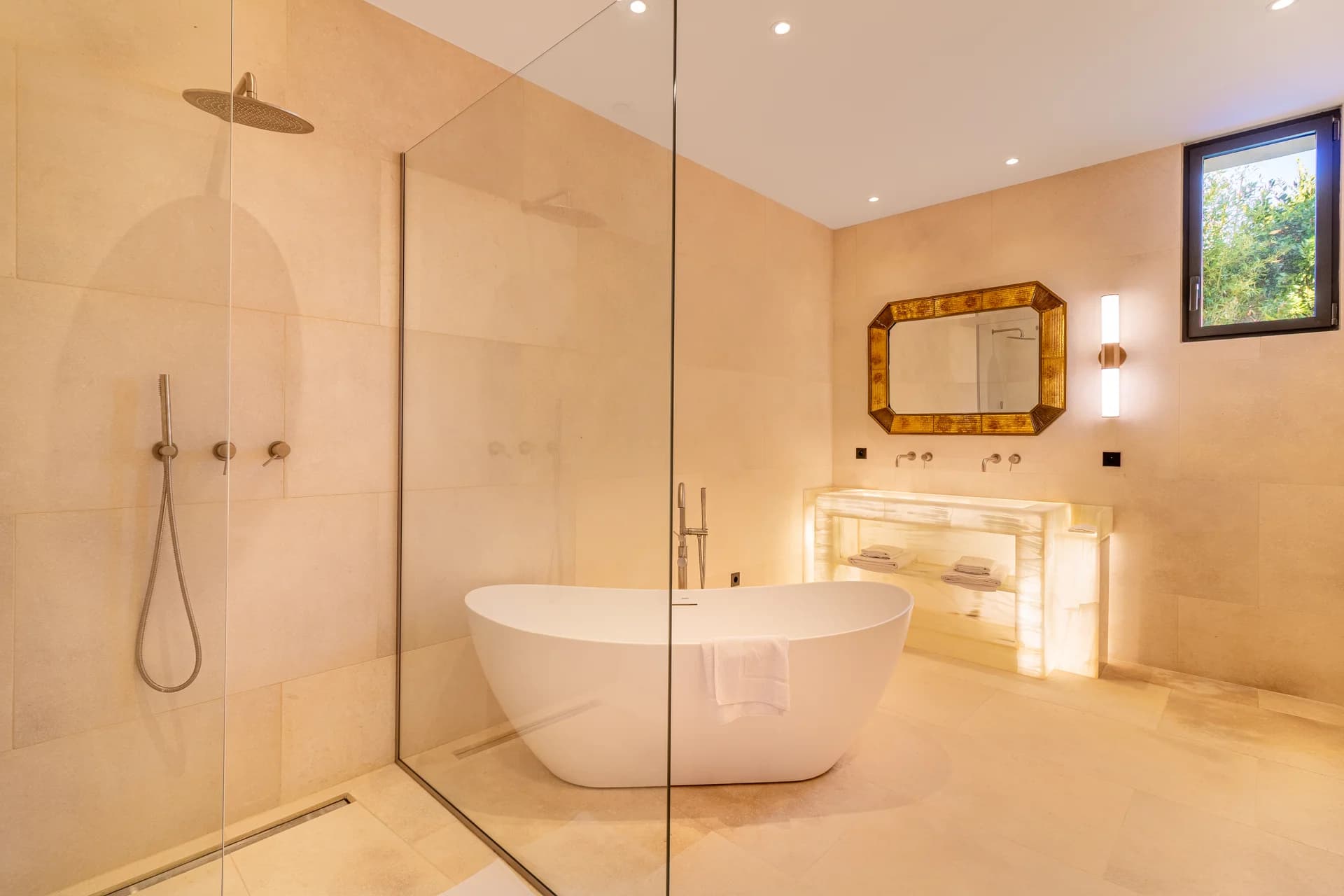 Salle de bain en travertin, baignoire îlot et miroir doré
