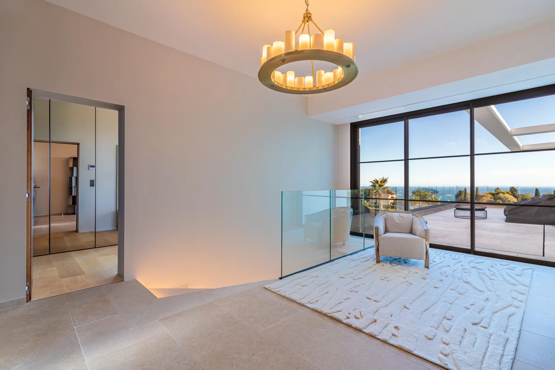 Salon aux tons sable, lustre en laiton et baies pleine hauteur